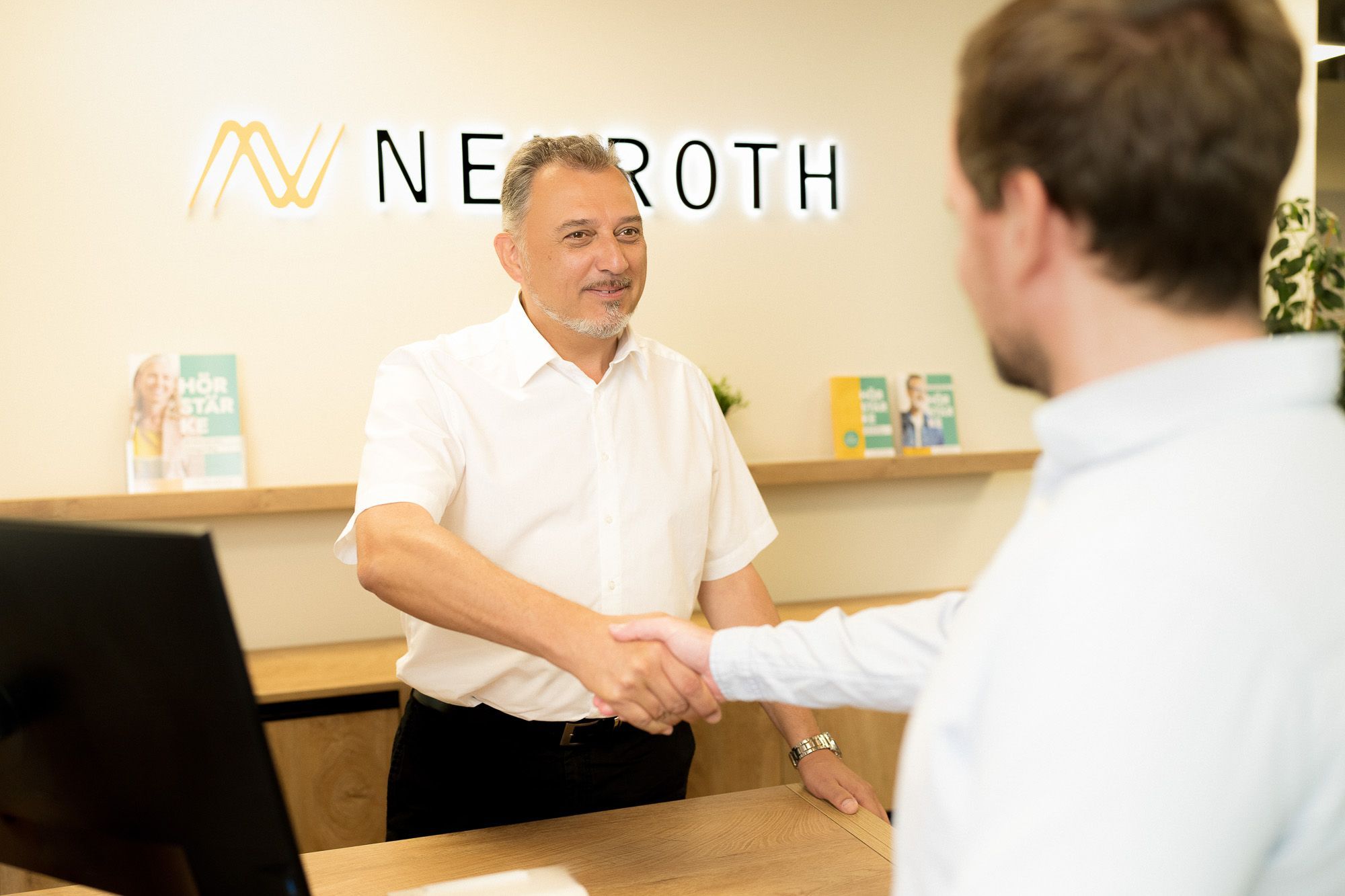 audioprothesiste accueille les clients a la reception en leur serrant la main