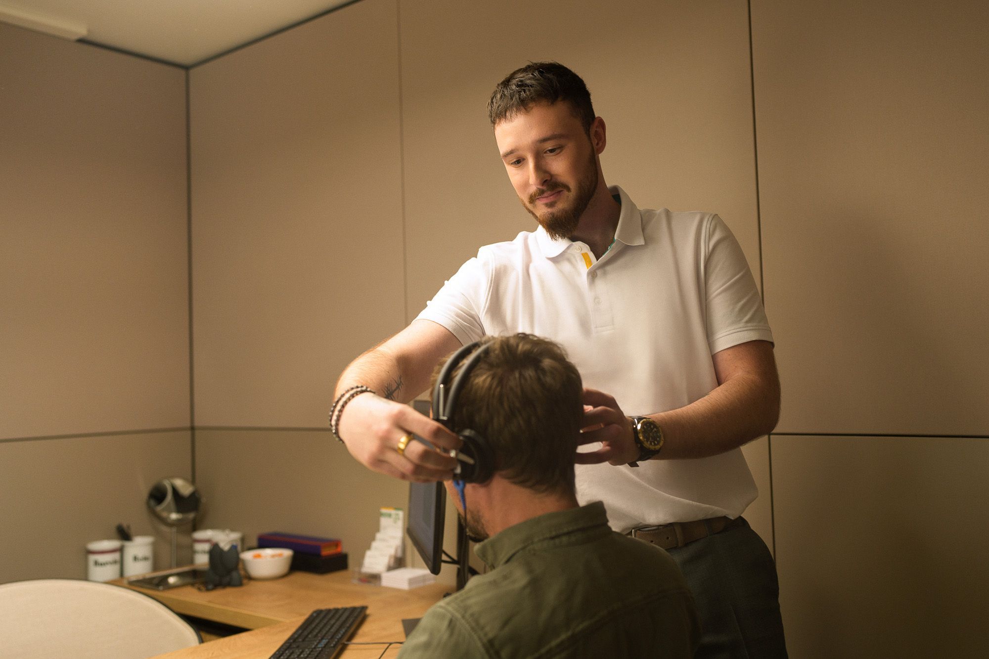audioprothesiste place un casque sur la cabine d'ecoute d'un client